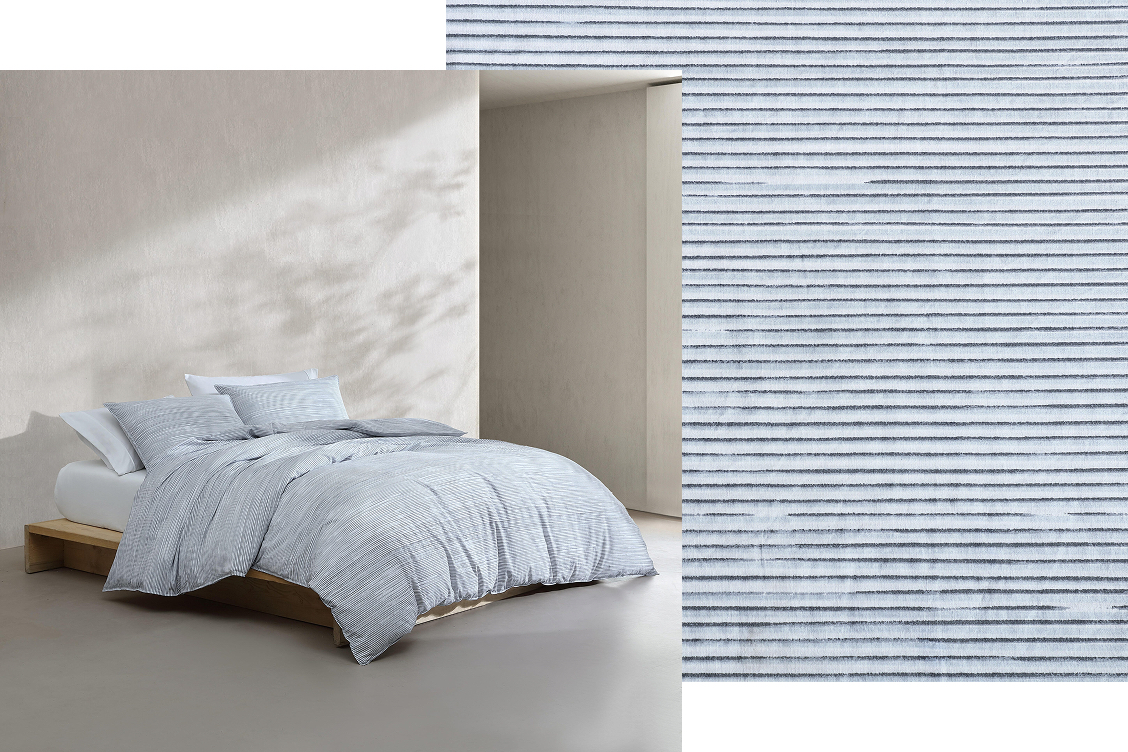 Bed near window made with striped white and blue sheets and sheet fabric swatch layered behind image.