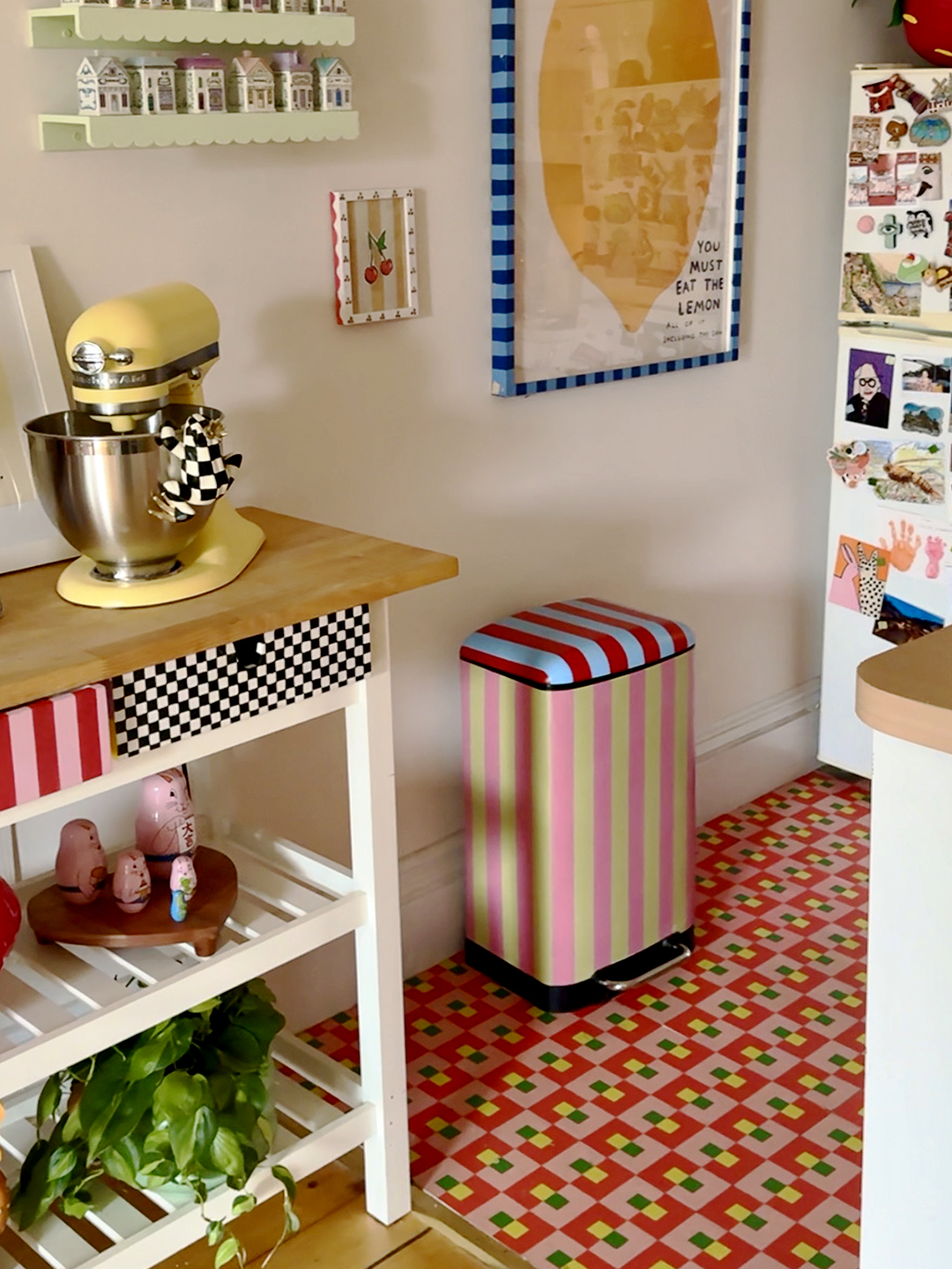 blue, red, pink, and green striped trash can in a kitchen