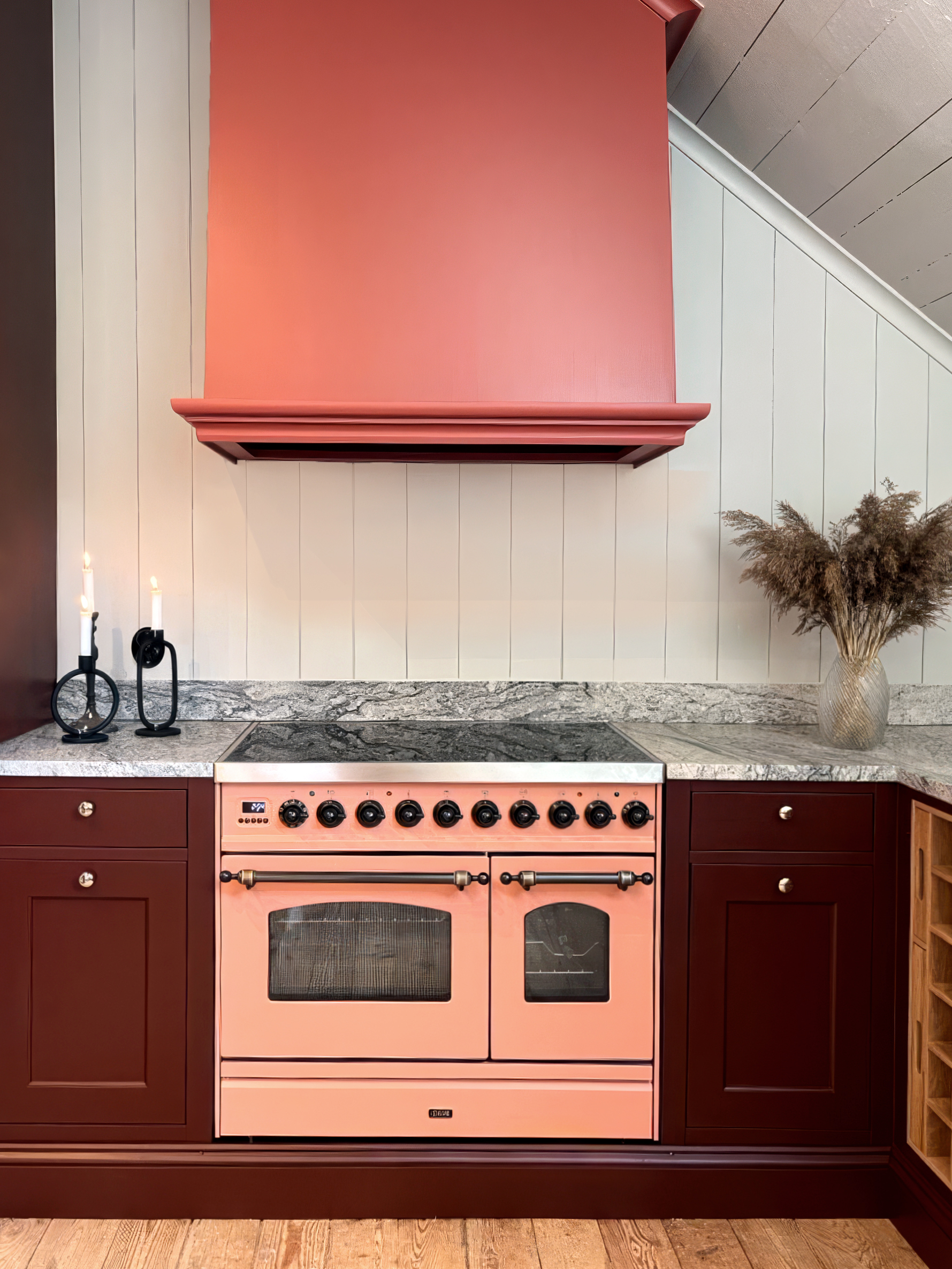 Close-up of apricot colored kitchen stove with burgundy cabinets and grey countertop.
