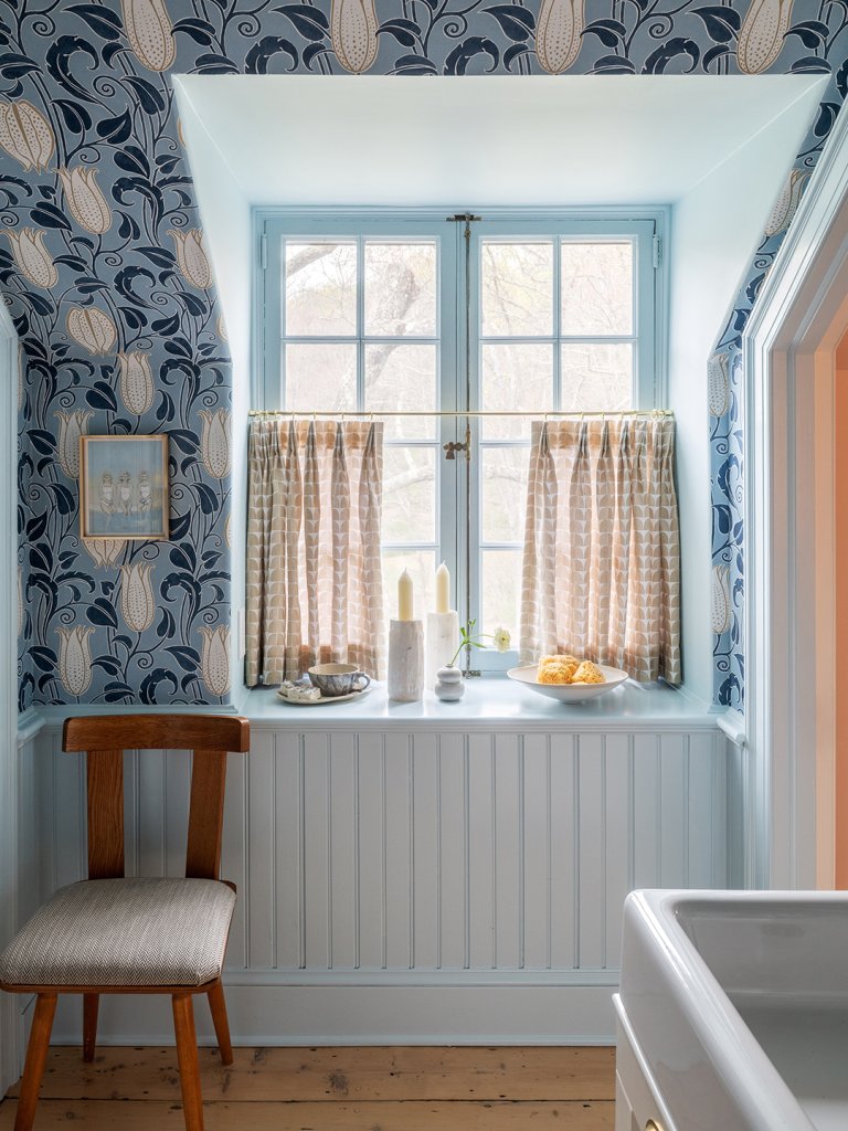 wallpapered room with cafe curtains and window