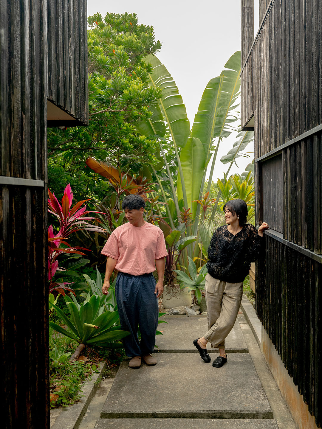 brother and sister leaning on house exterior