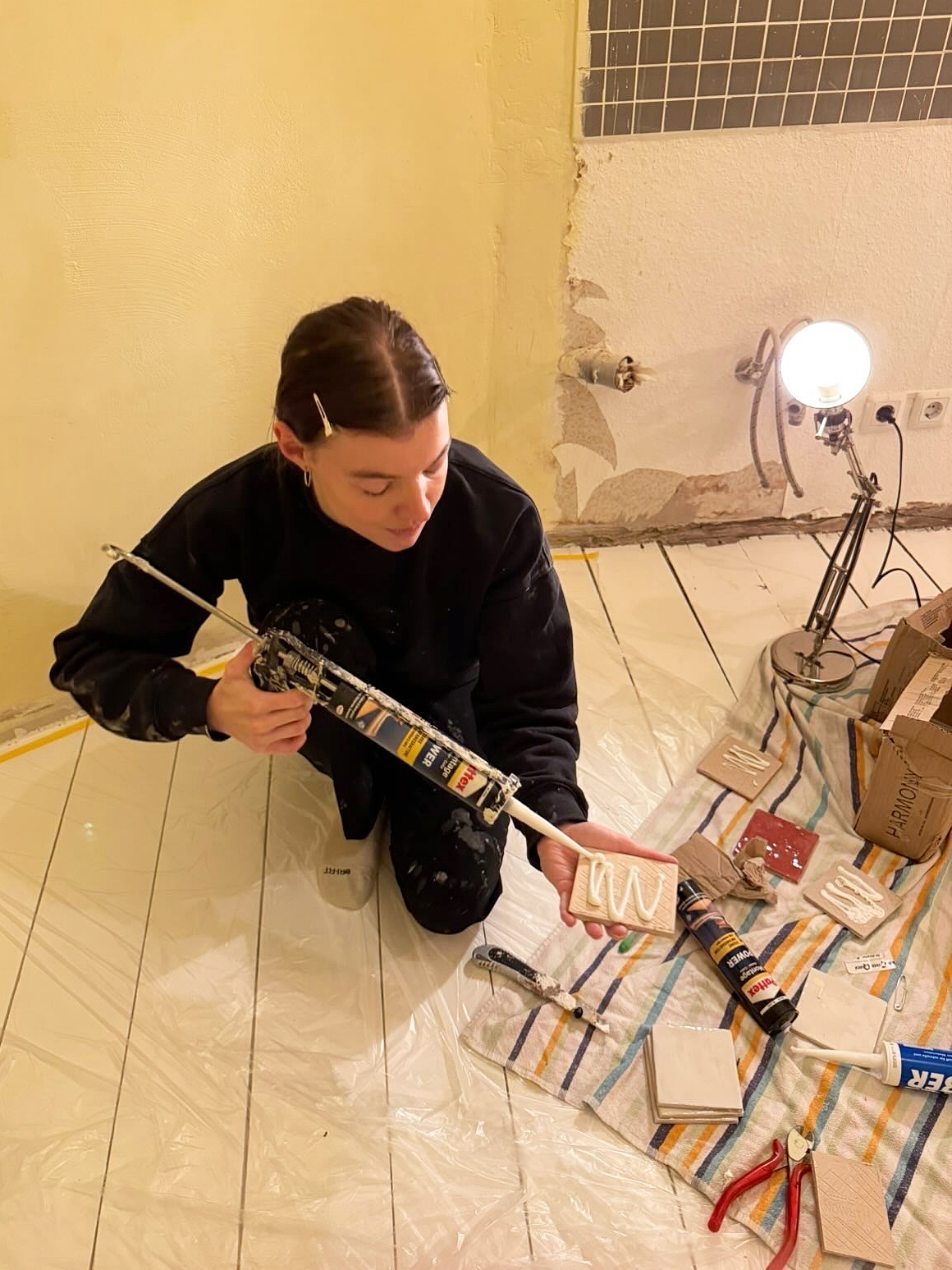 woman adding caulk to the back of a tile