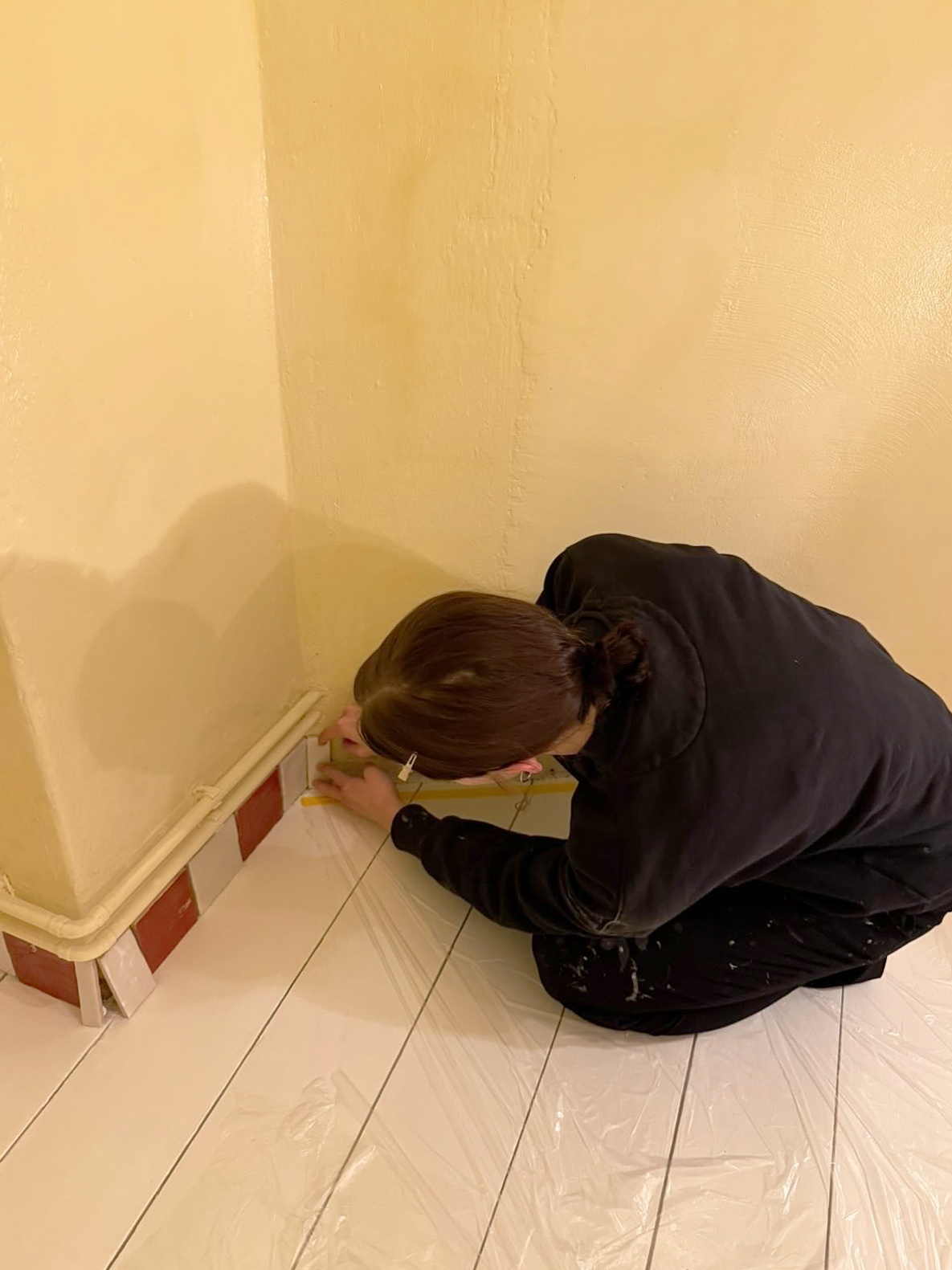 woman affixing a tile as a baseboard