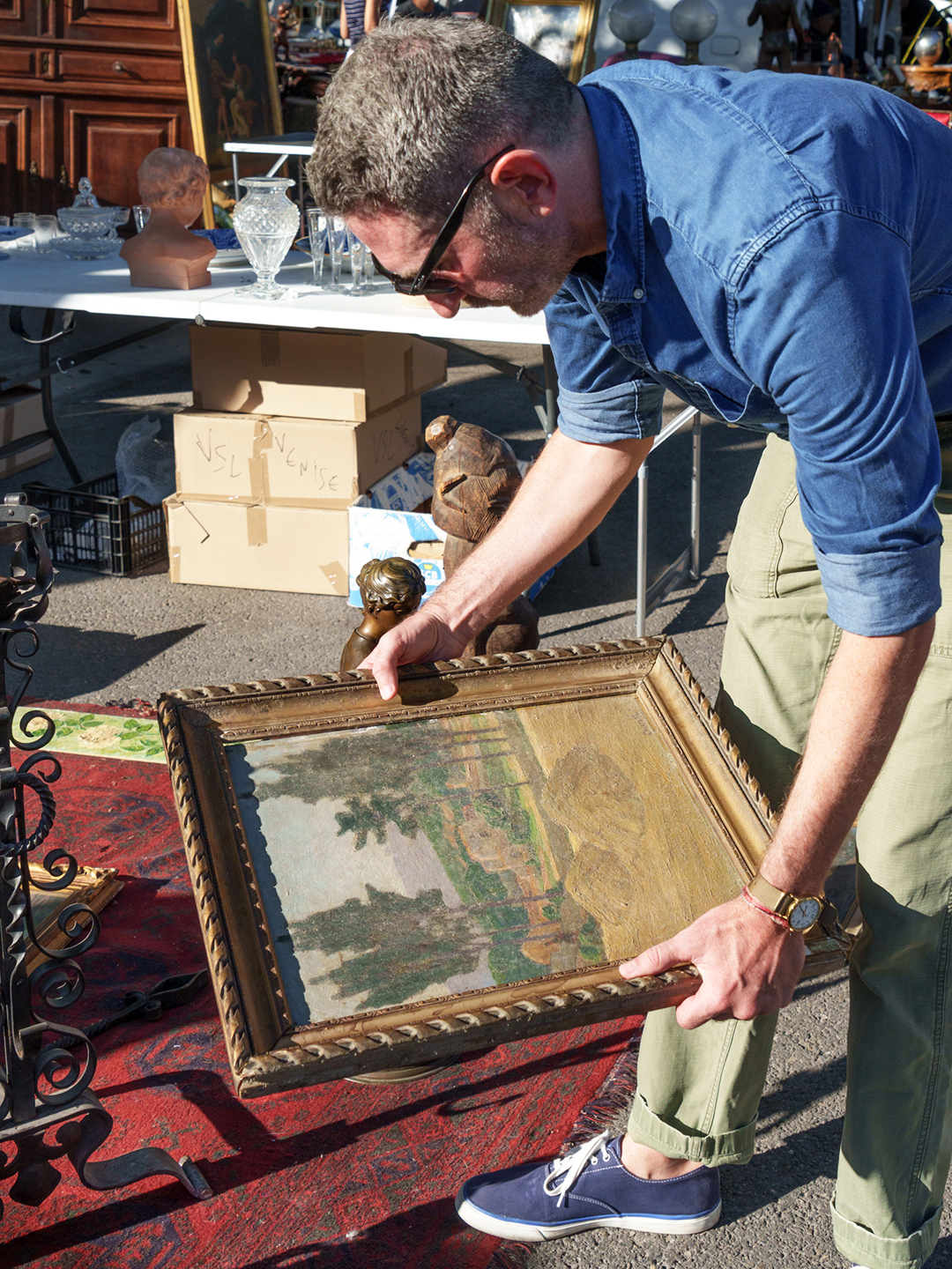 man holding a vintage painting at a flea