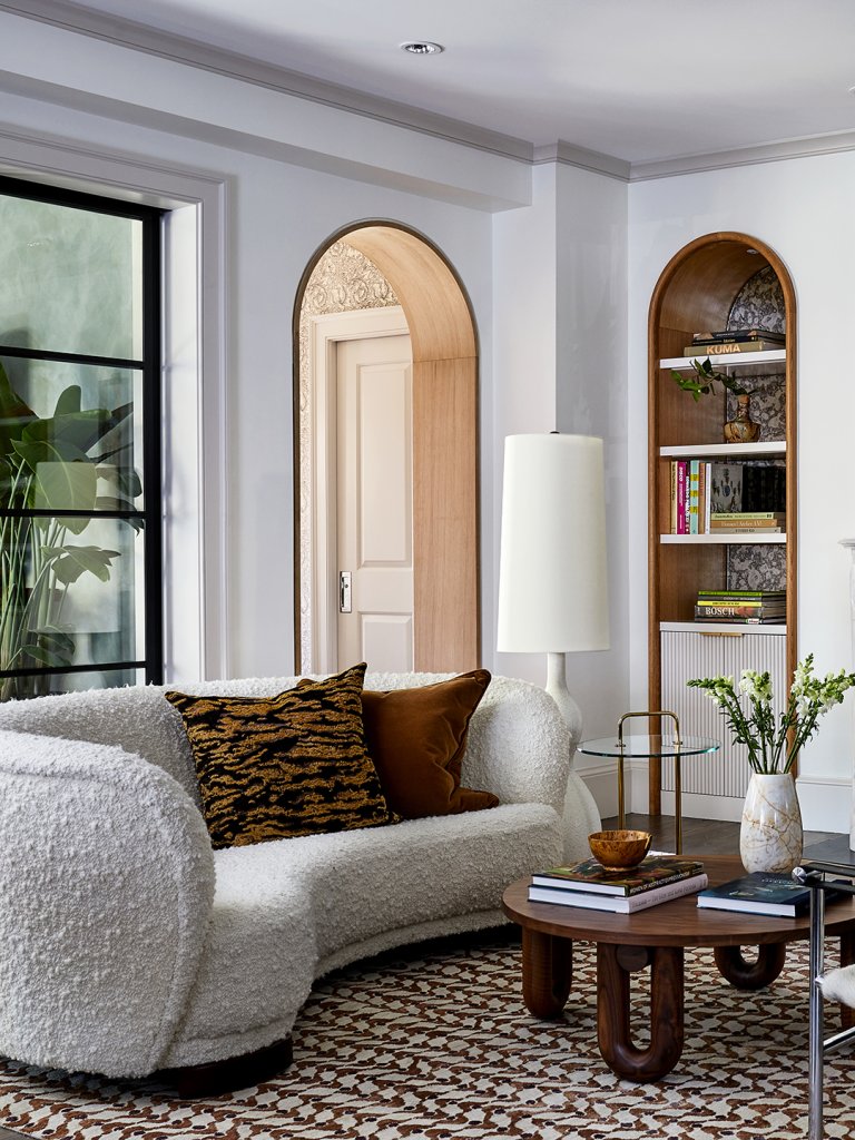 living room with arched doorways, a white mantle, and a white curved sofa