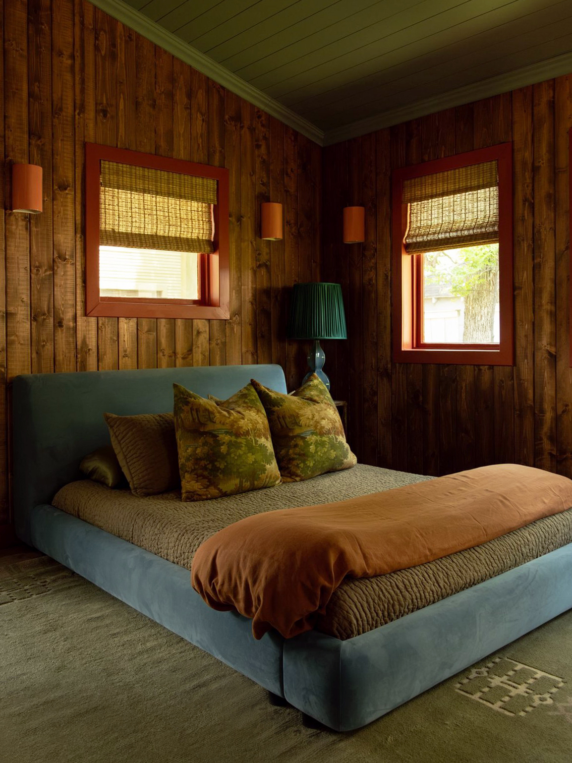 Cabin bedroom with blue velvet bed frame and brown bedding.
