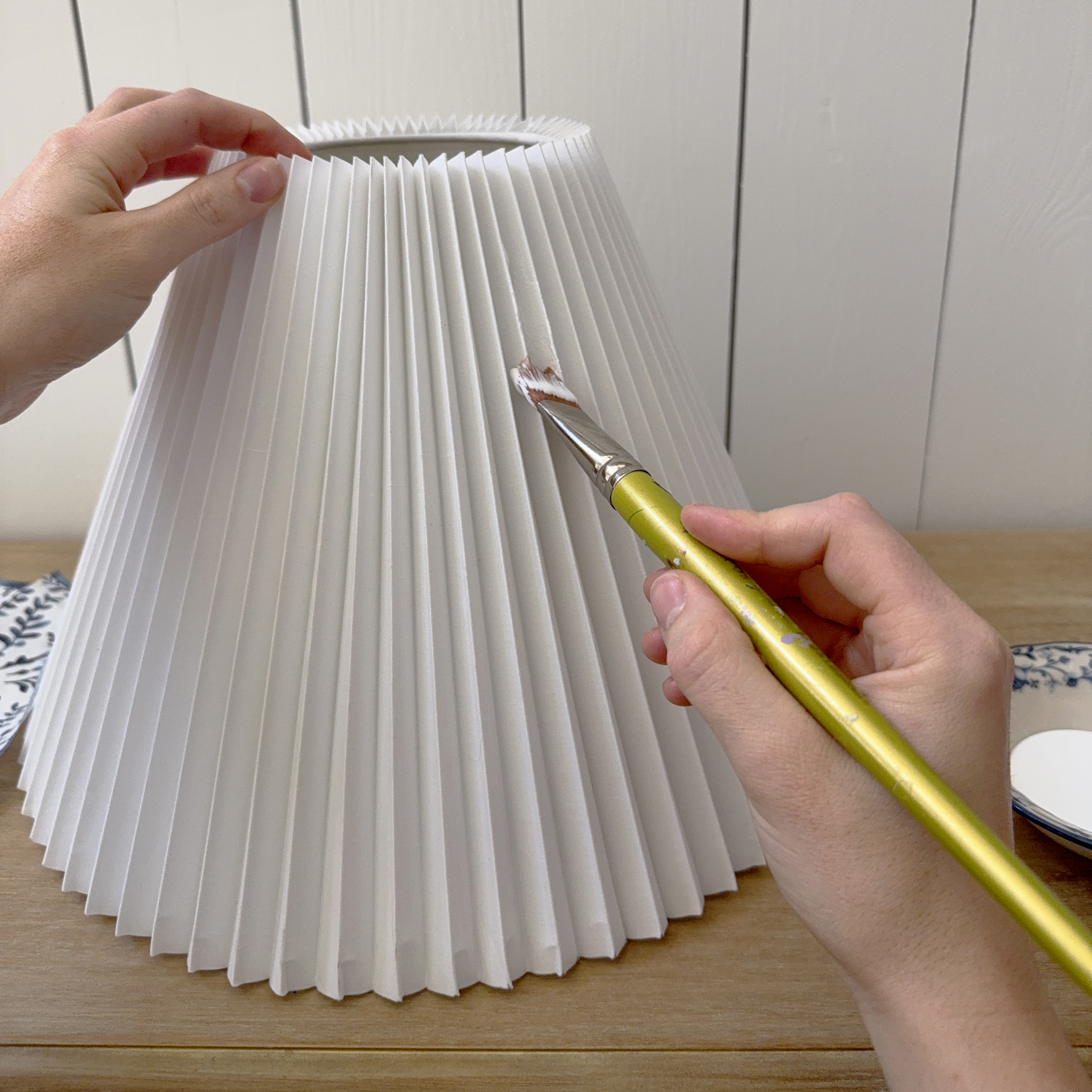painting glue onto a white paper lampshade