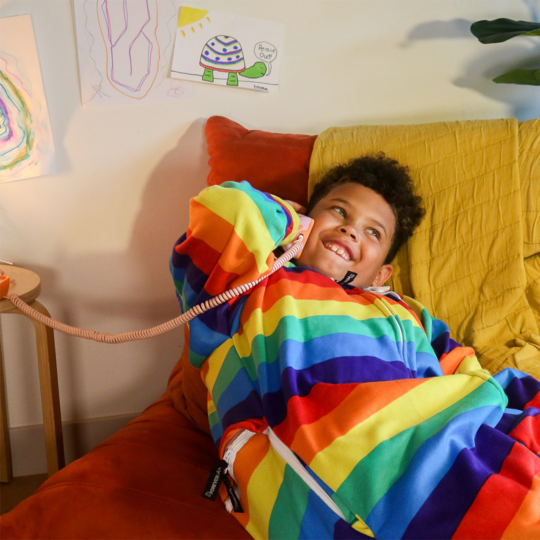 child in bed talking on a yellow landline