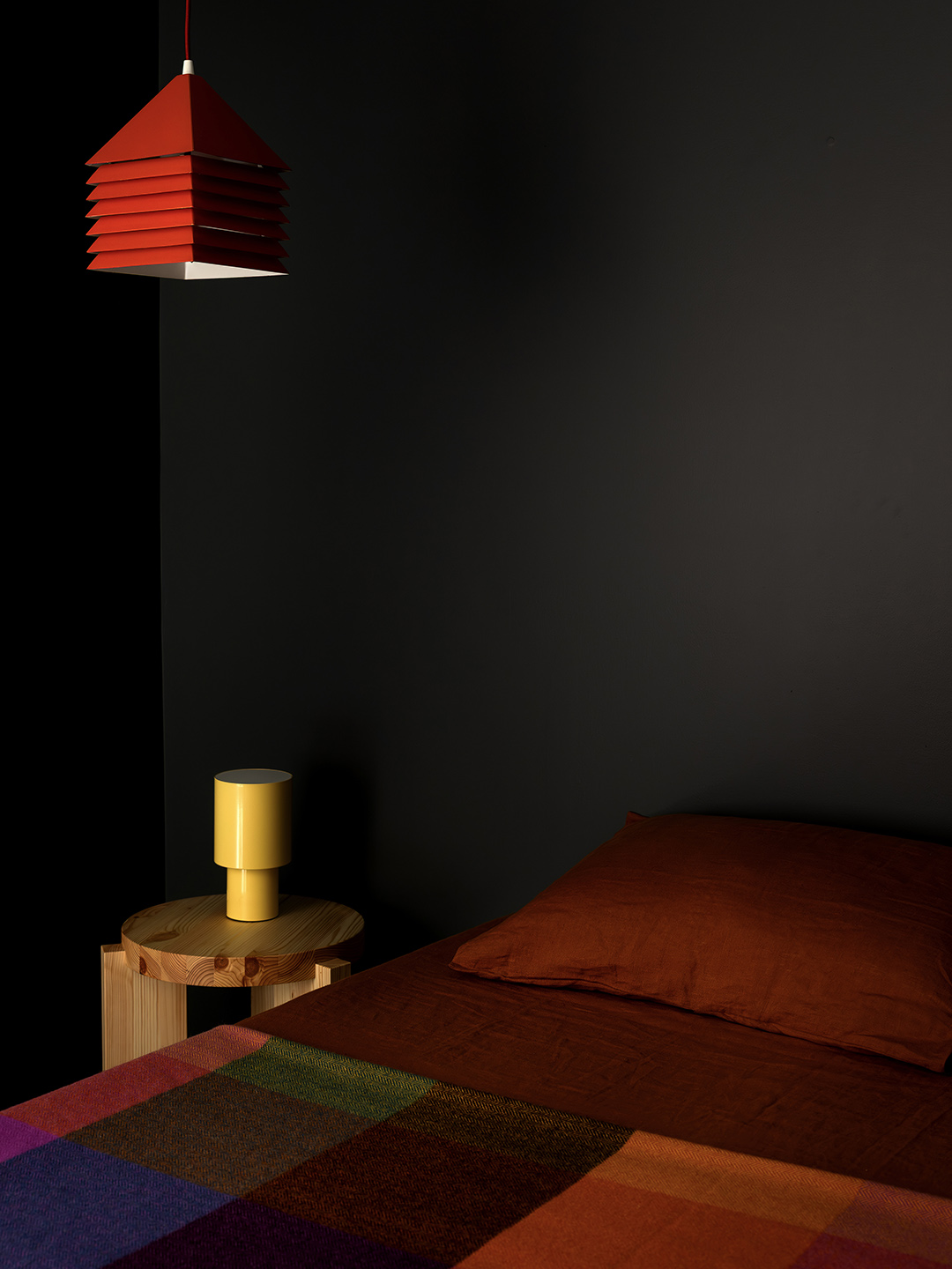dark bedroom with red bedding and pendant light