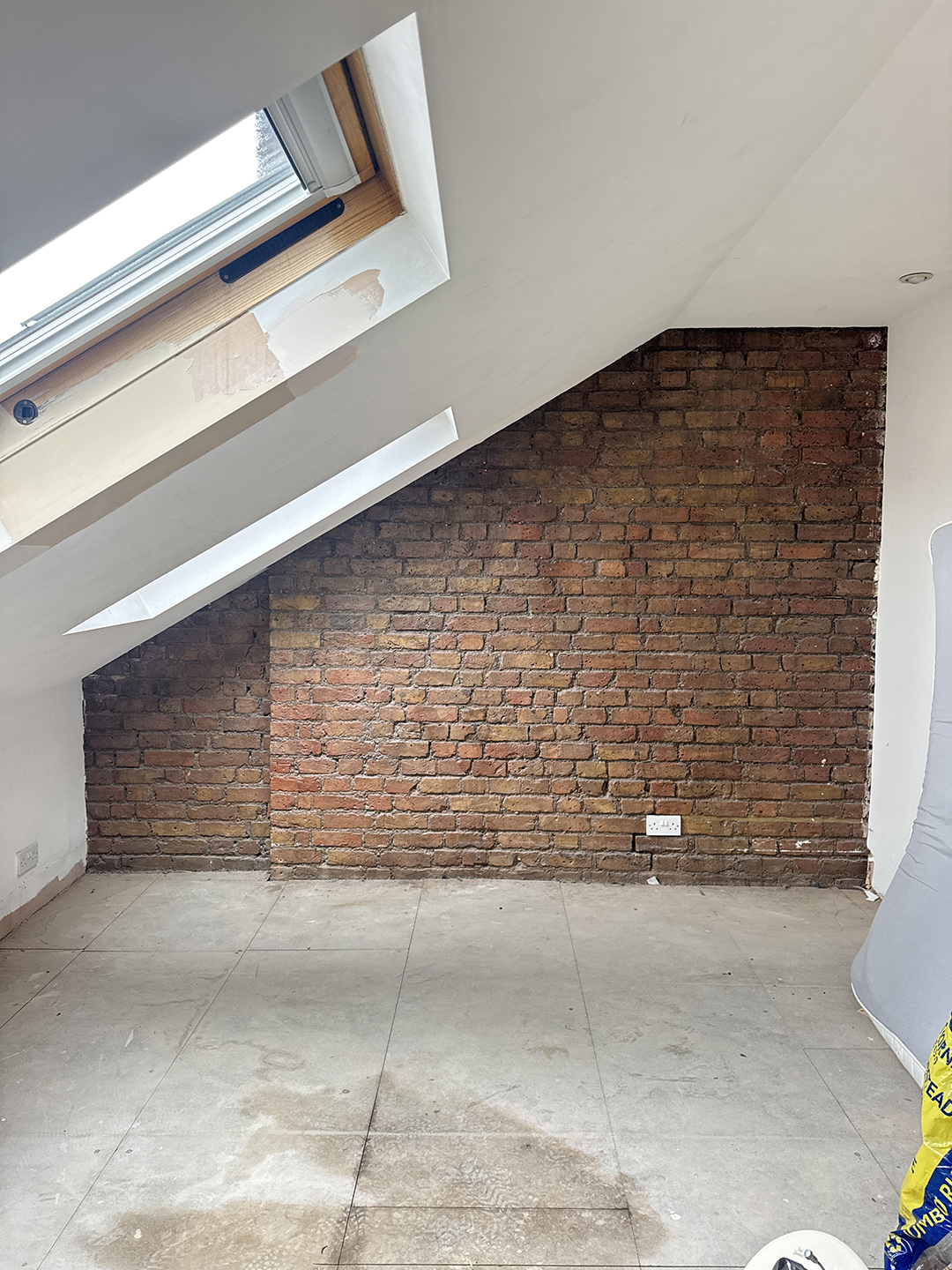 room with angled ceiling and brick wall