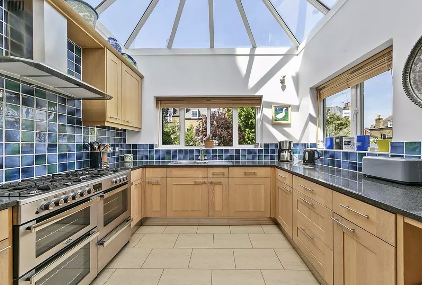kitchen with blue tile backsplash and skylight