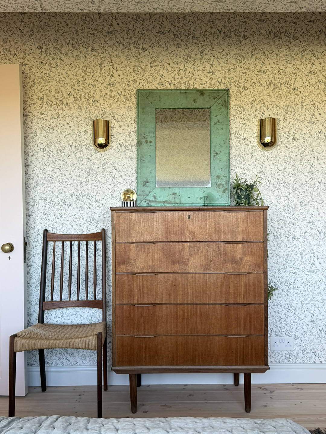 wallpapered room with wood dresser, mirror, and wood chair