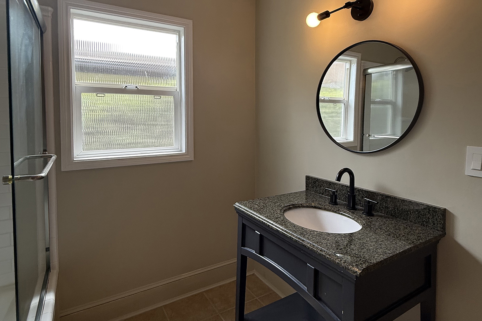 bathroom with small sink and round mirror