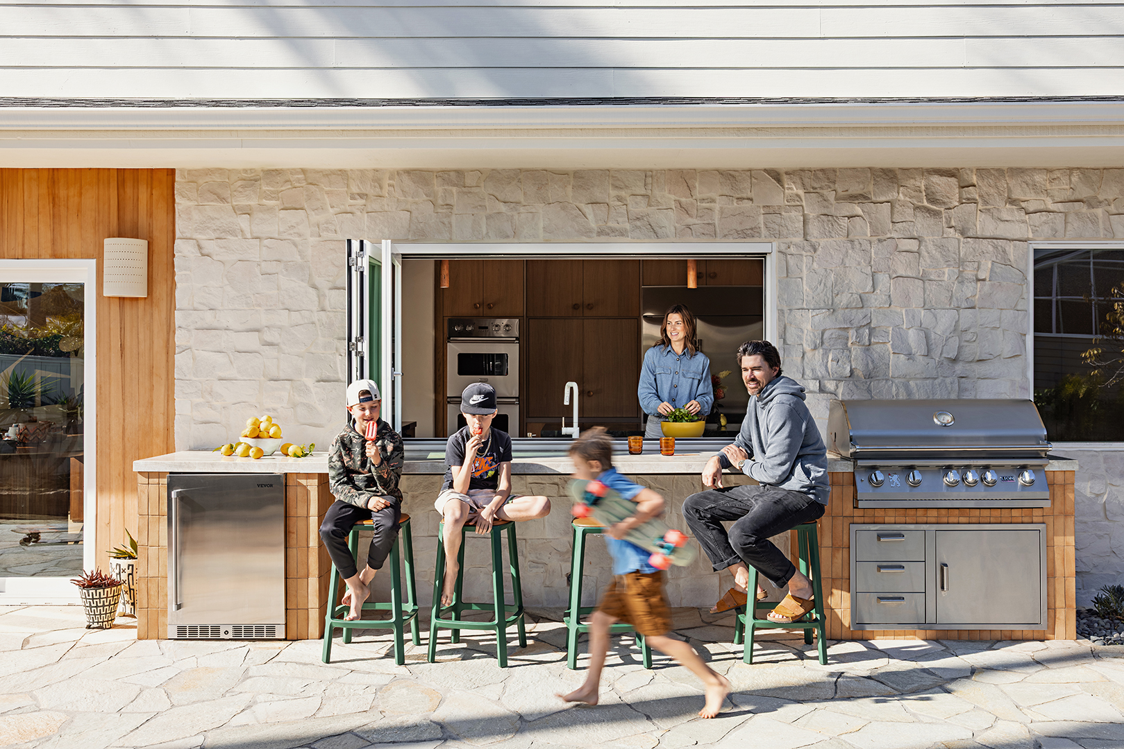 family of mom, dad, and three boys at their indoor-outdoor kitchen