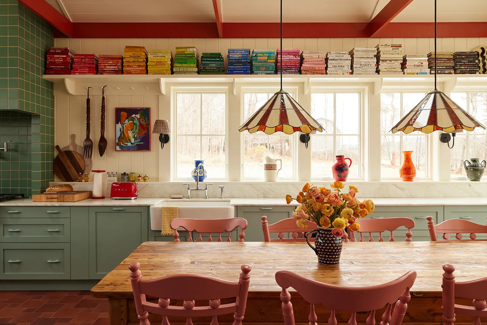 colorful kitchen with wood table, pink chairs, and teal cabinets