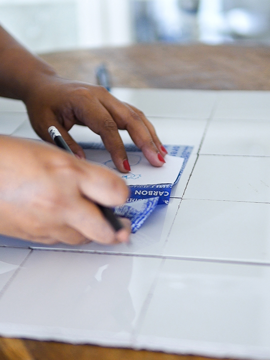 person tracing a design onto a tile