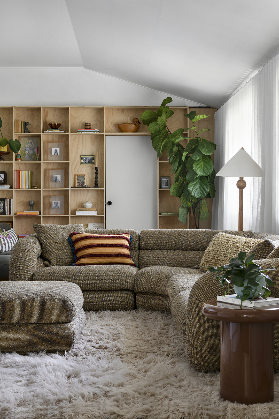 living room with rounded sofa and plywood shelves