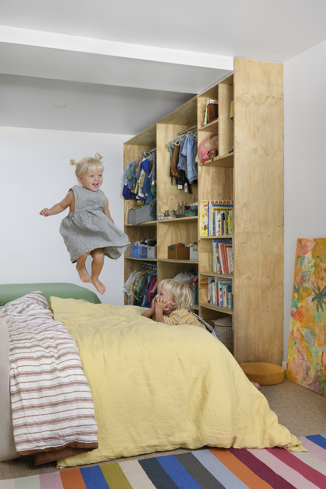 kids jumping on bed in a room with plywood shelves