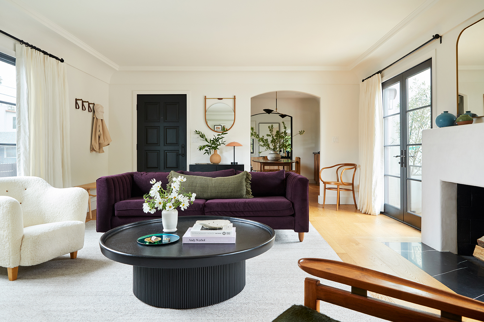 living room with purple sofa and white chair and round coffee table