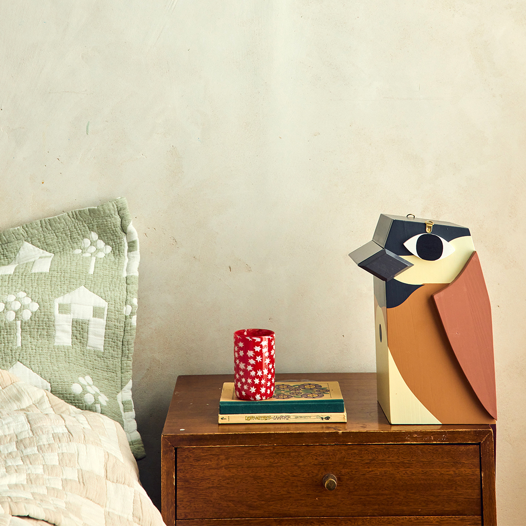 colorful wooden birdhouse sitting on bedside table