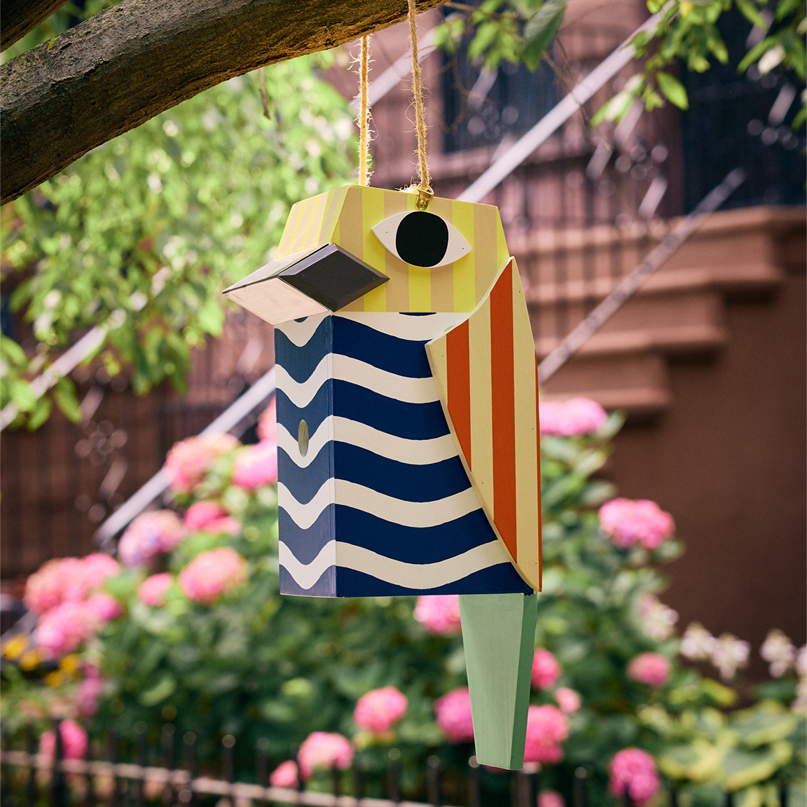 colorful wooden birdhouse hanging in tree