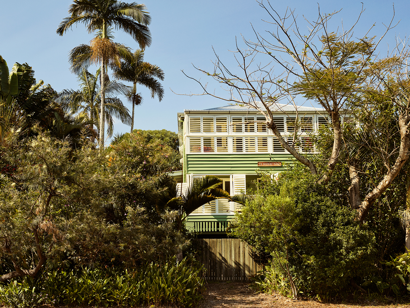 green and white home tucked into lush landscape