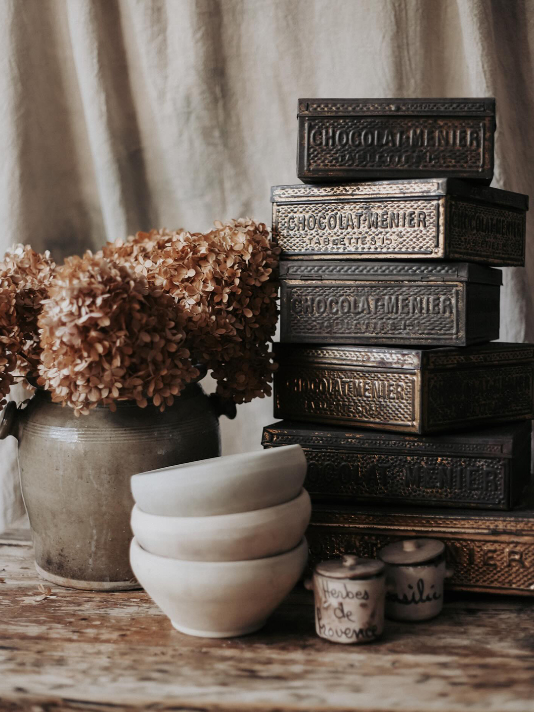 stack of antique brass boxes and hydrangeas in a vase