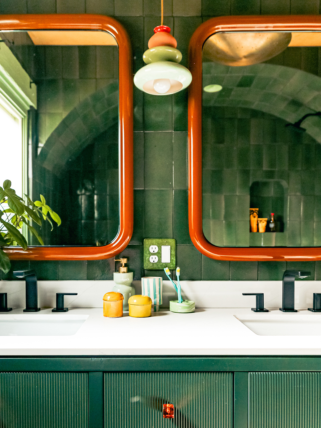 green-tiled bathroom with double mirrors and sinks