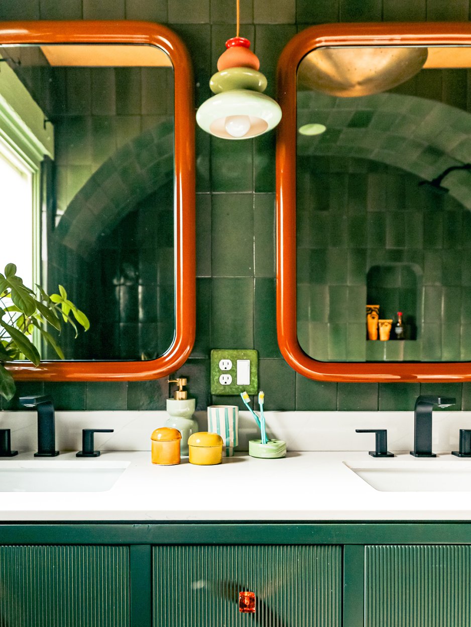 green-tiled bathroom with double mirrors and sinks