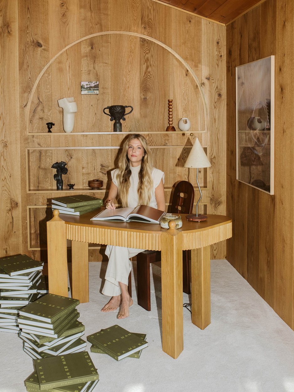 woman at a desk in a wood room signing books