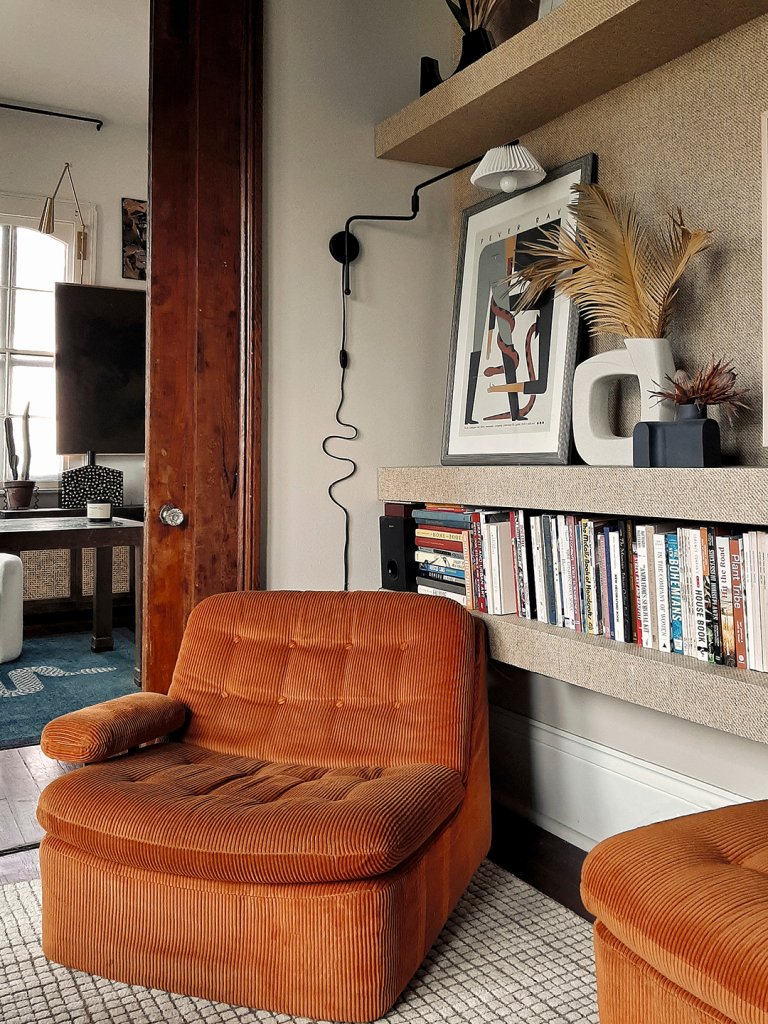 corner of a room with chair and a sconce with squiggly cord above