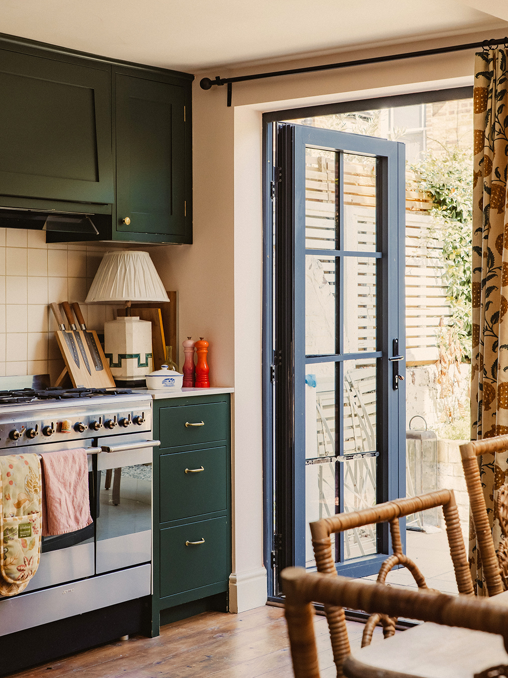 corner of kitchen with green cabinets and back door open