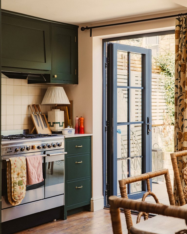 corner of kitchen with green cabinets and back door open