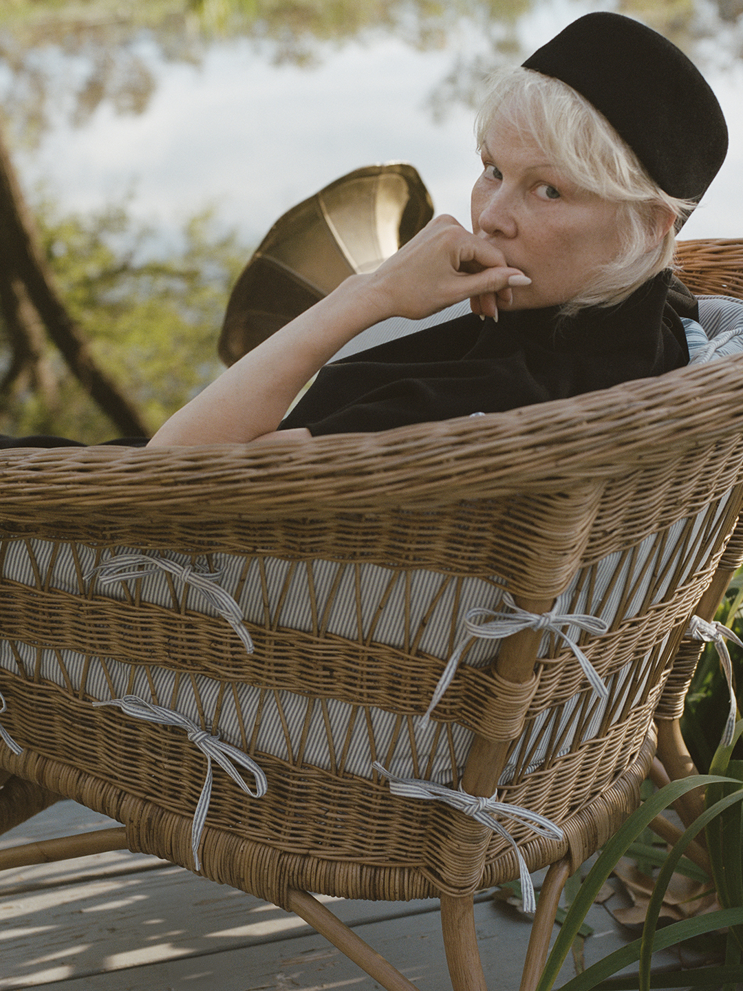 pamela anderson sitting in a rattan chair