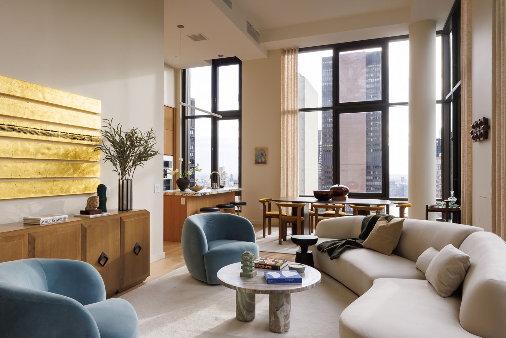living room with white sofa, two chairs, and gold artwork