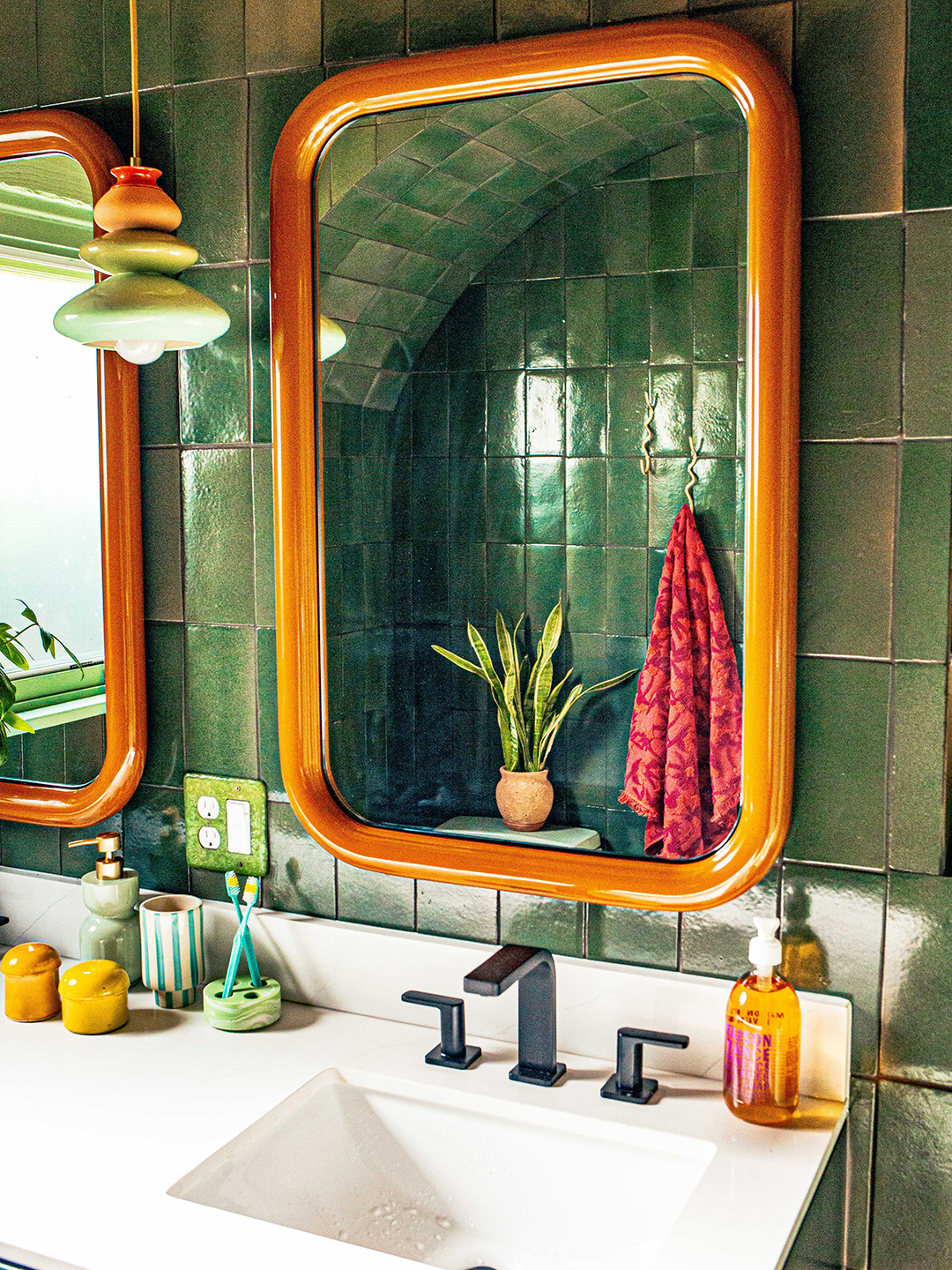 green-tiled bathroom with double mirrors and sinks