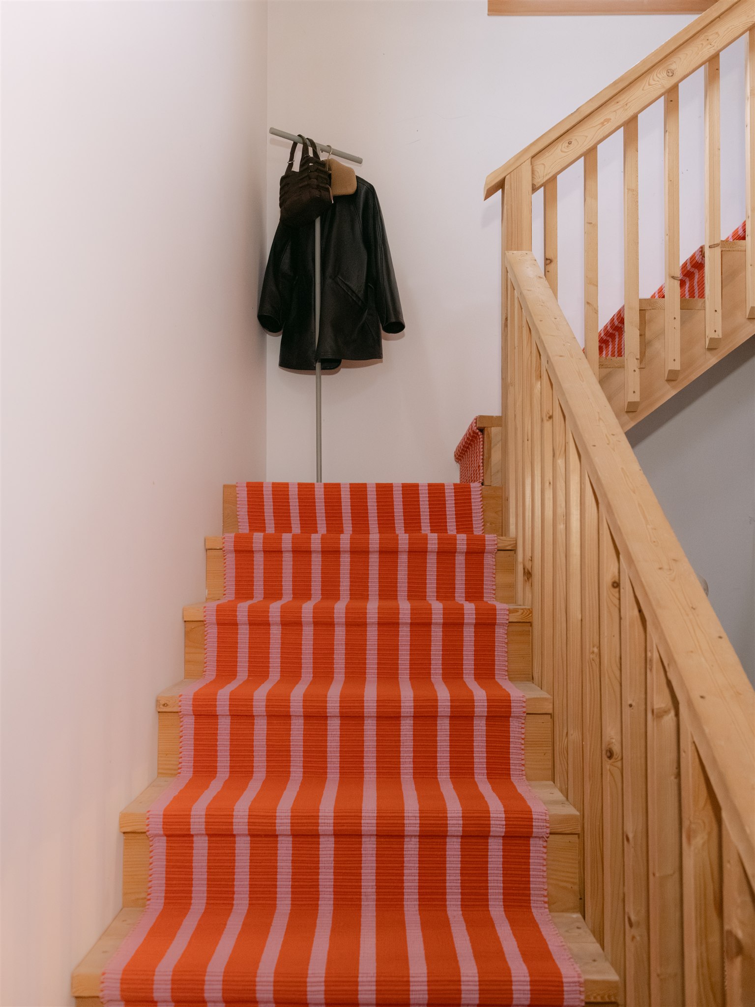 wooden stairs that turn at landing with striped runner rug