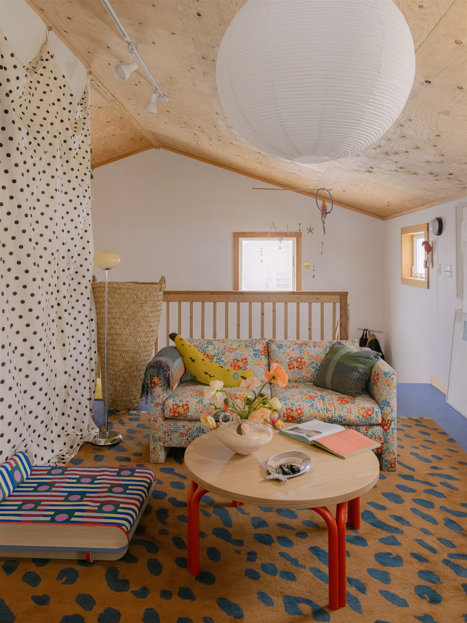 white room with slanted wood ceiling, colorful furniture, polka dot curtain
