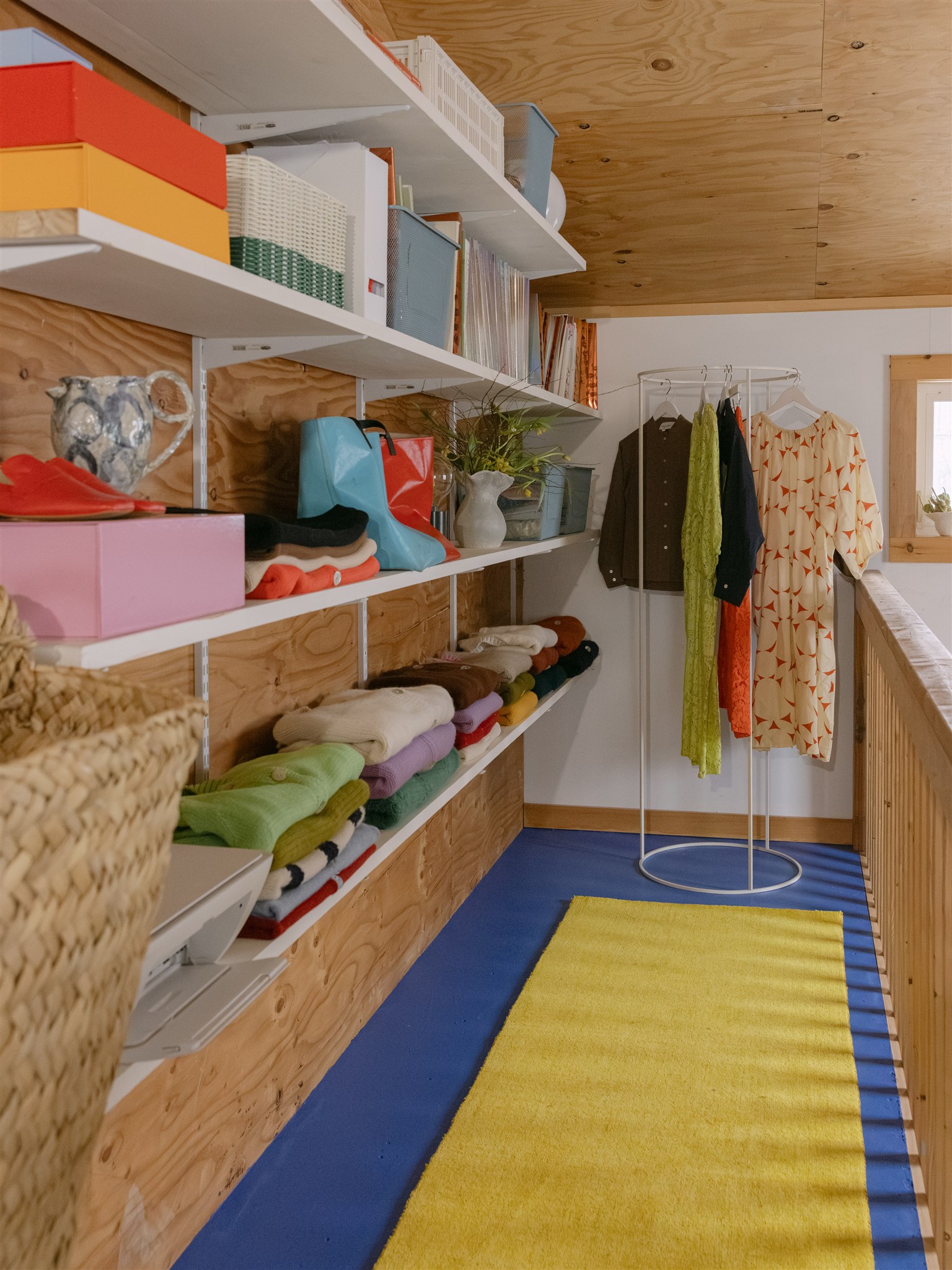 stair landing with open shelves styled with sweaters and vases