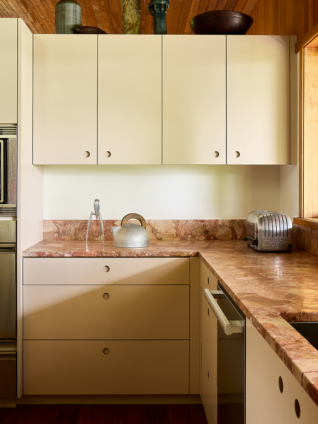 creamy yellow kitchen with pink marble backsplash and counters