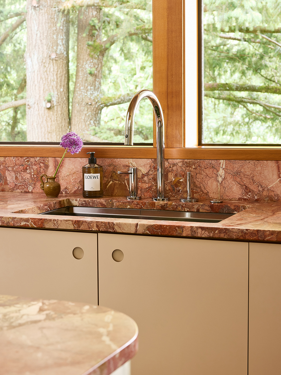 kitchen sink with pink marble backsplash and counters