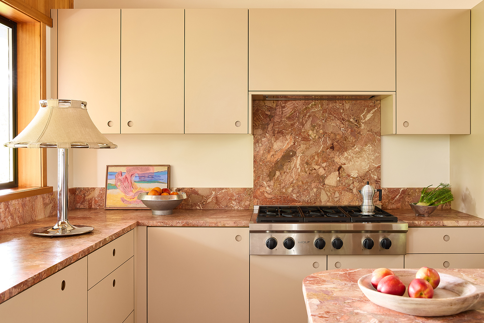 creamy yellow kitchen with pink marble backsplash and counters
