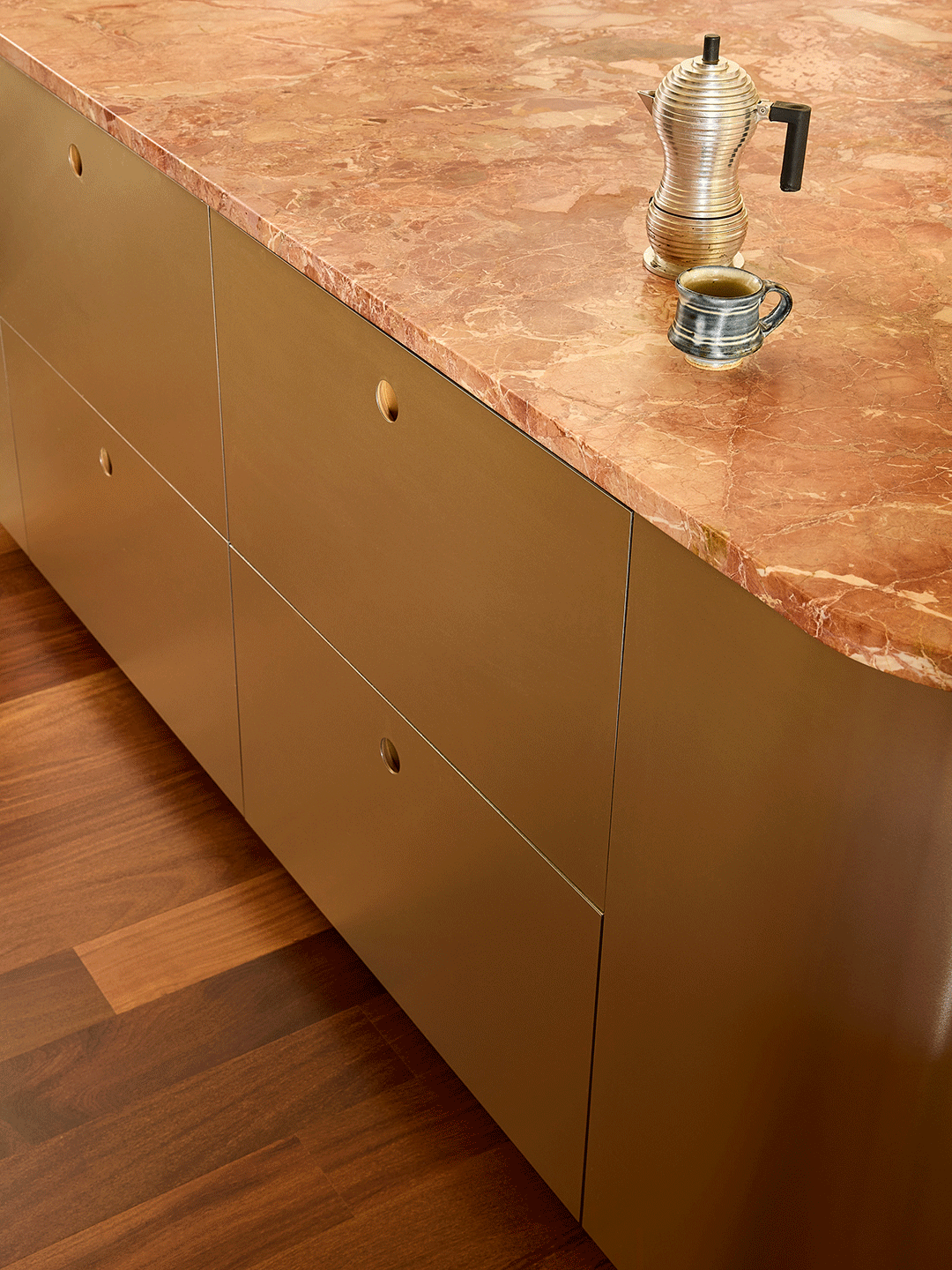 kitchen island with pink marble countertop and creamy yellow drawers