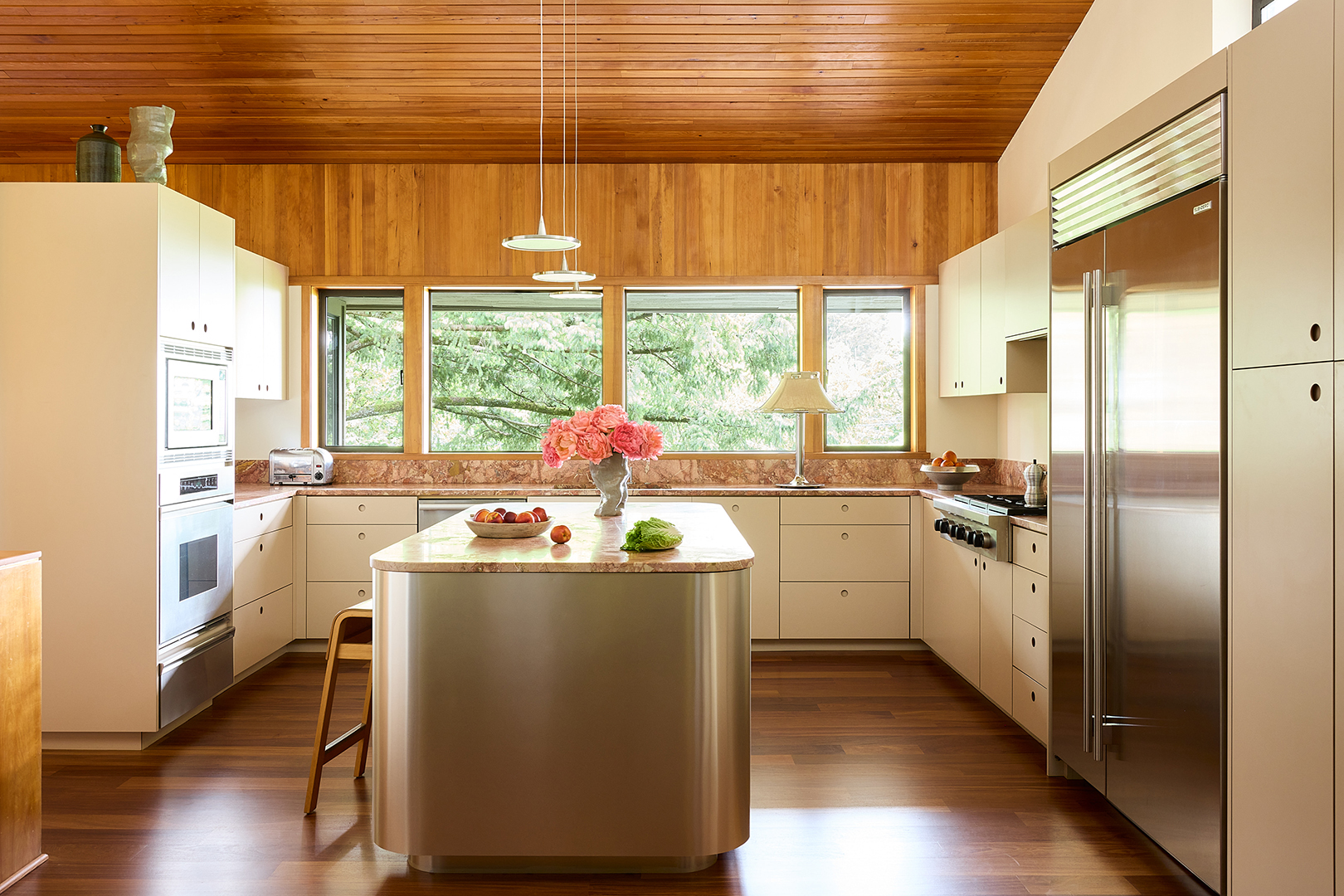 creamy yellow kitchen with pink marble backsplash and counters and metal island