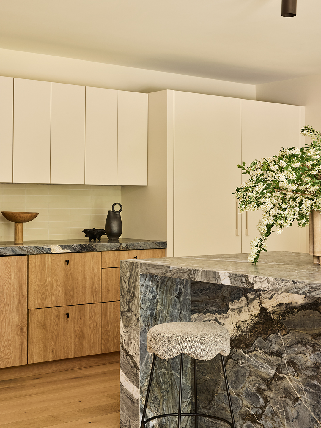 white kitchen with wood cabinetry and a. marble island