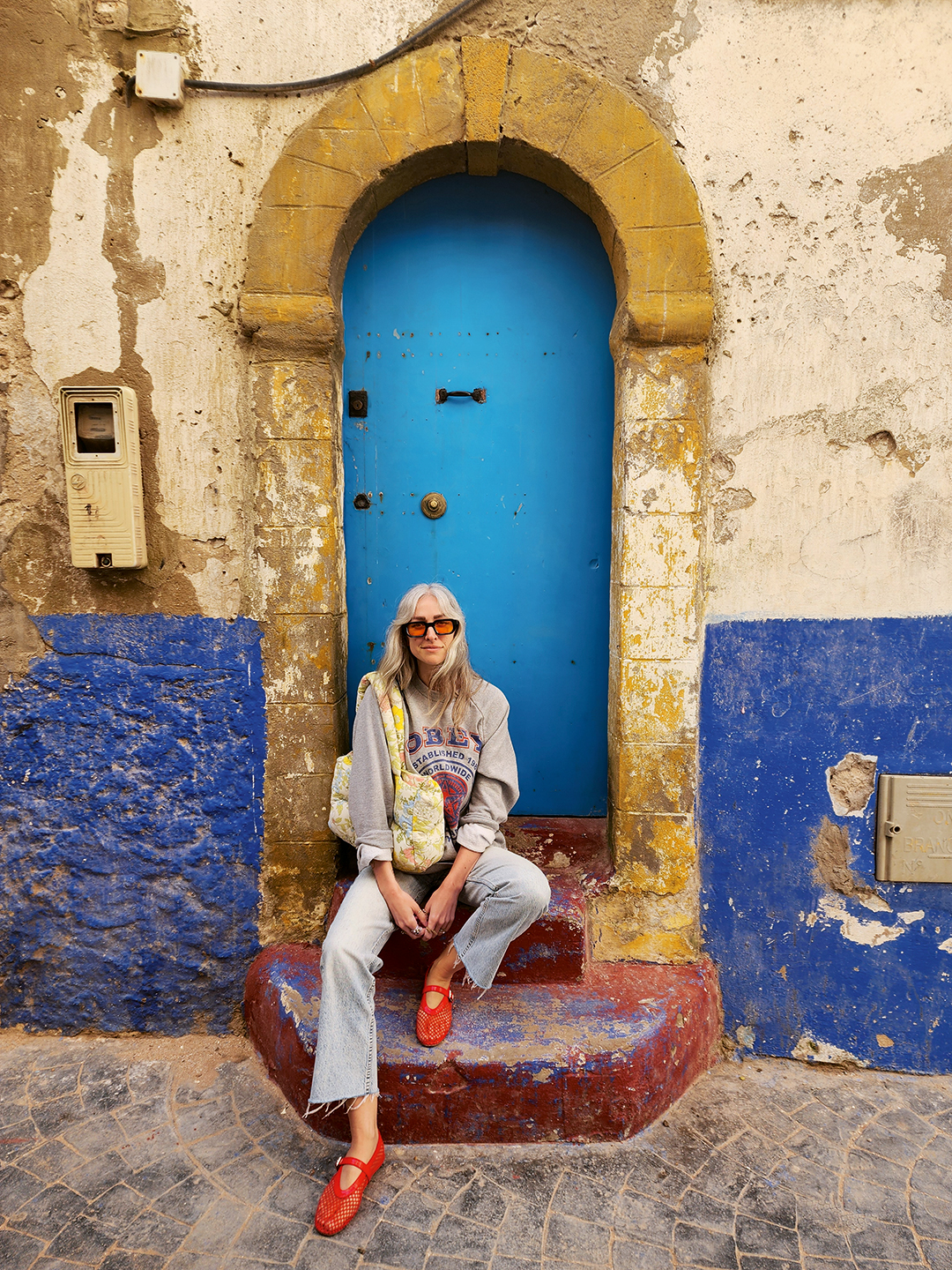woman on a step in front of a blue arched door