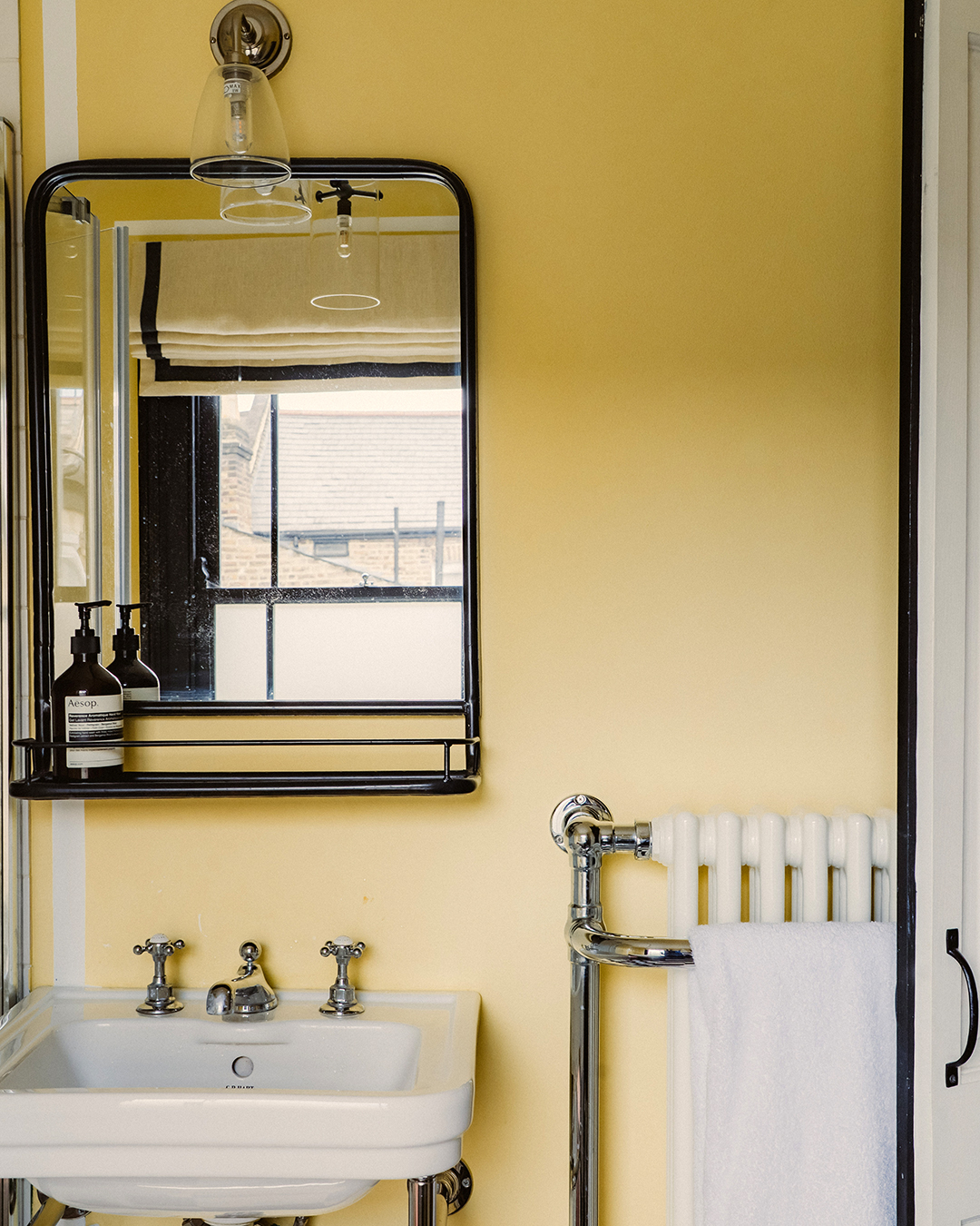 yellow bathroom with black framed mirror