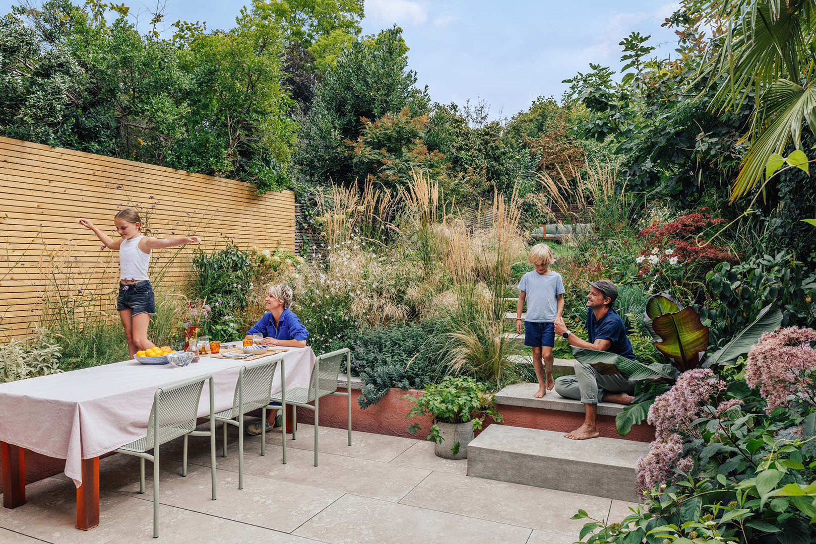 back yard with a family at a dinner table and garden