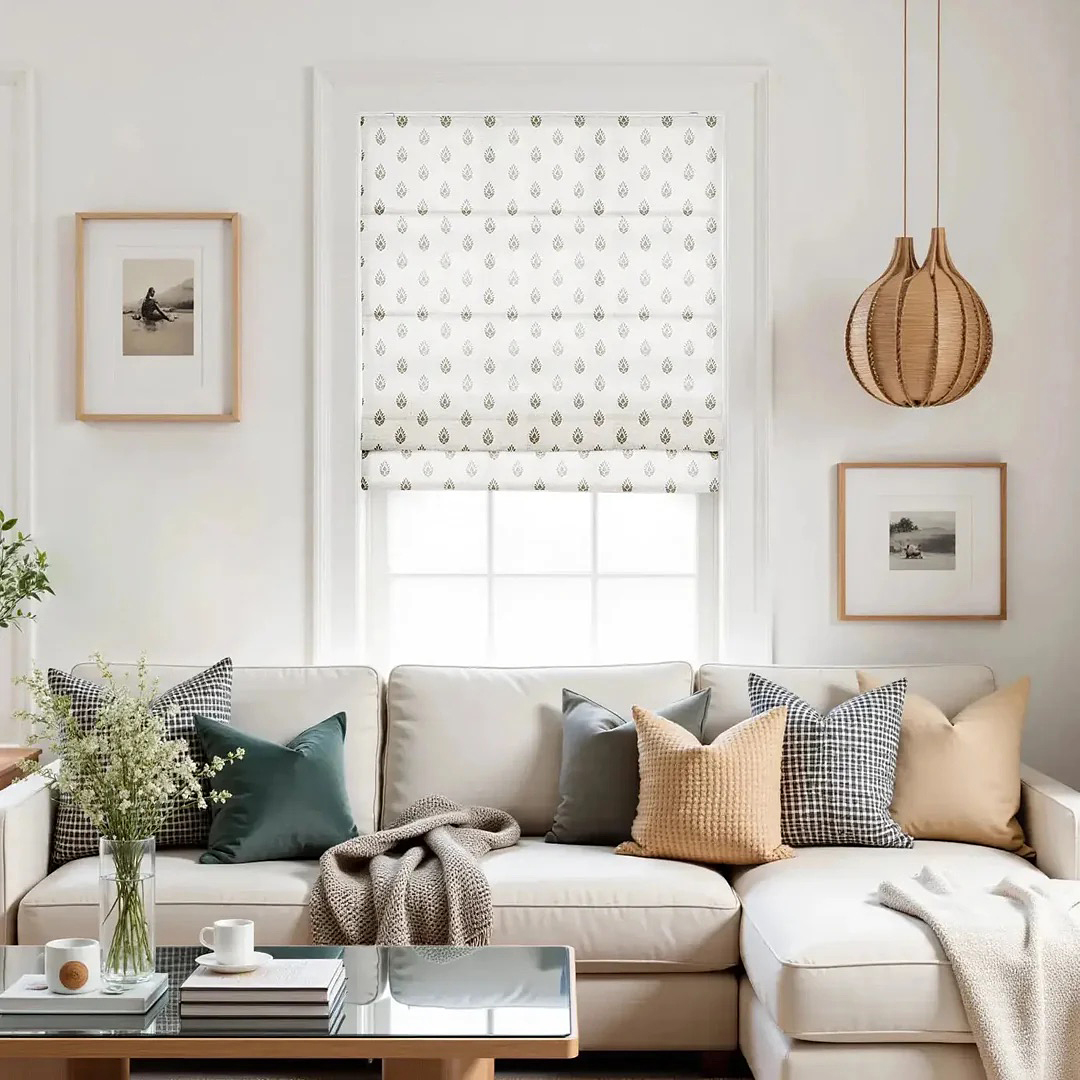 White living room with grey sofa, paintings on wall, and white Roman shades on window.