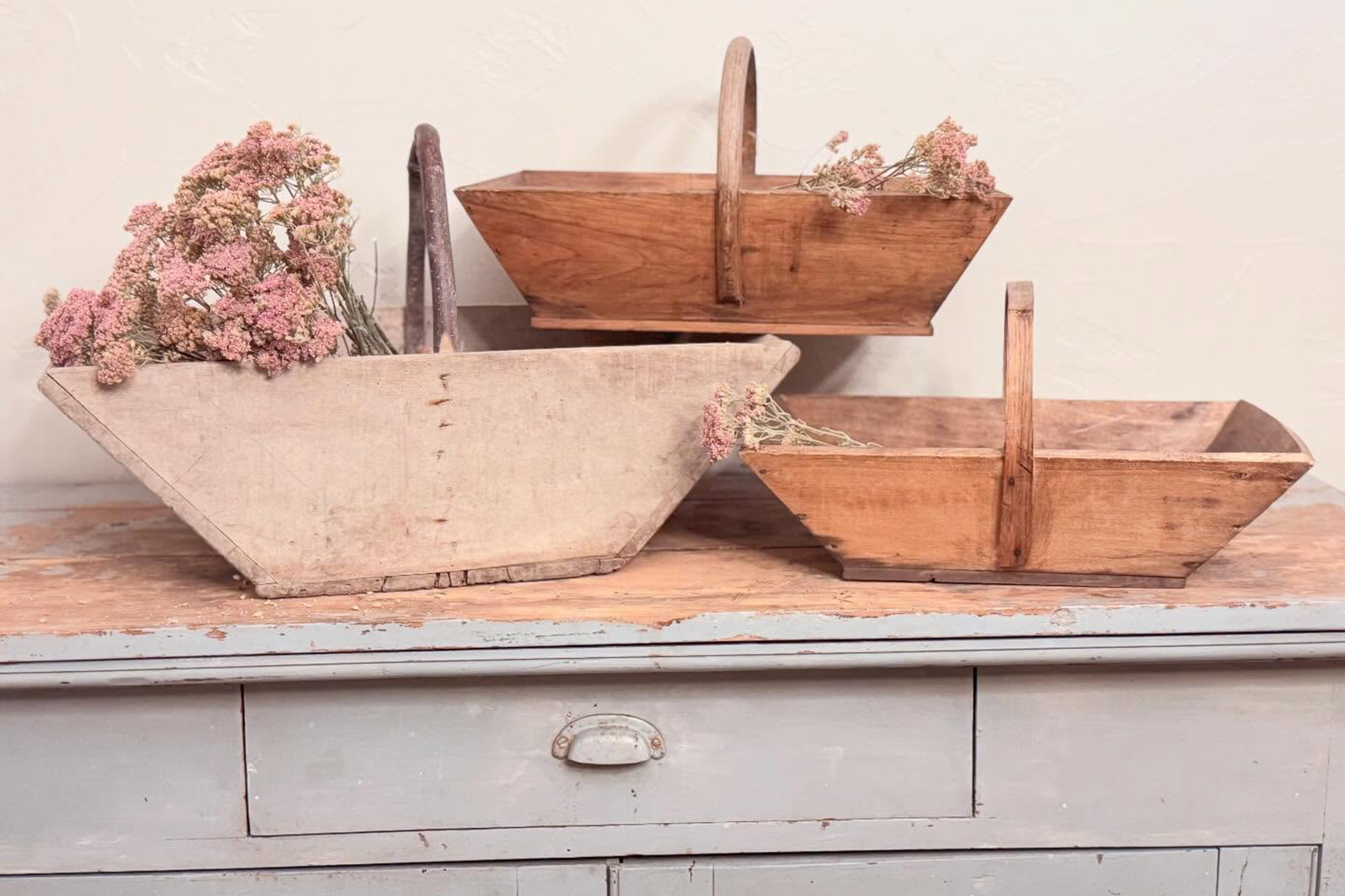 long angled wooden baskets holding flowers, on a dresser